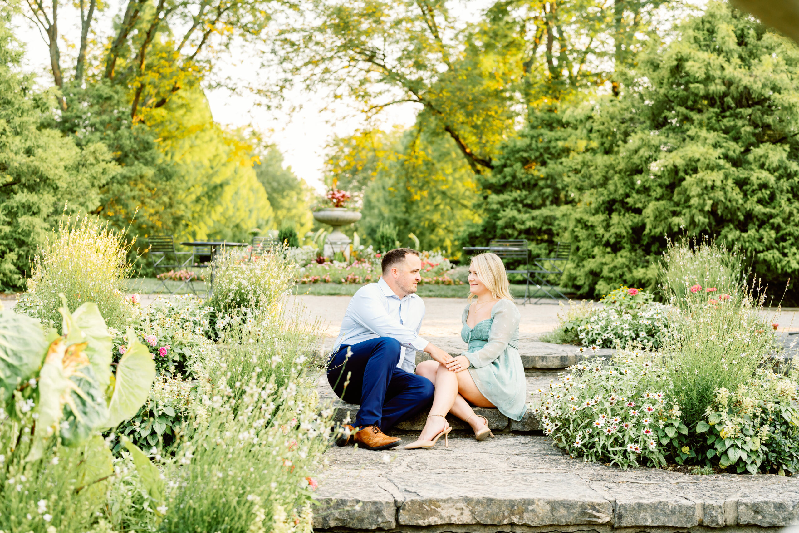 engaged man and woman sitting on the steps at Wegerzen Gardens Dayton OH
