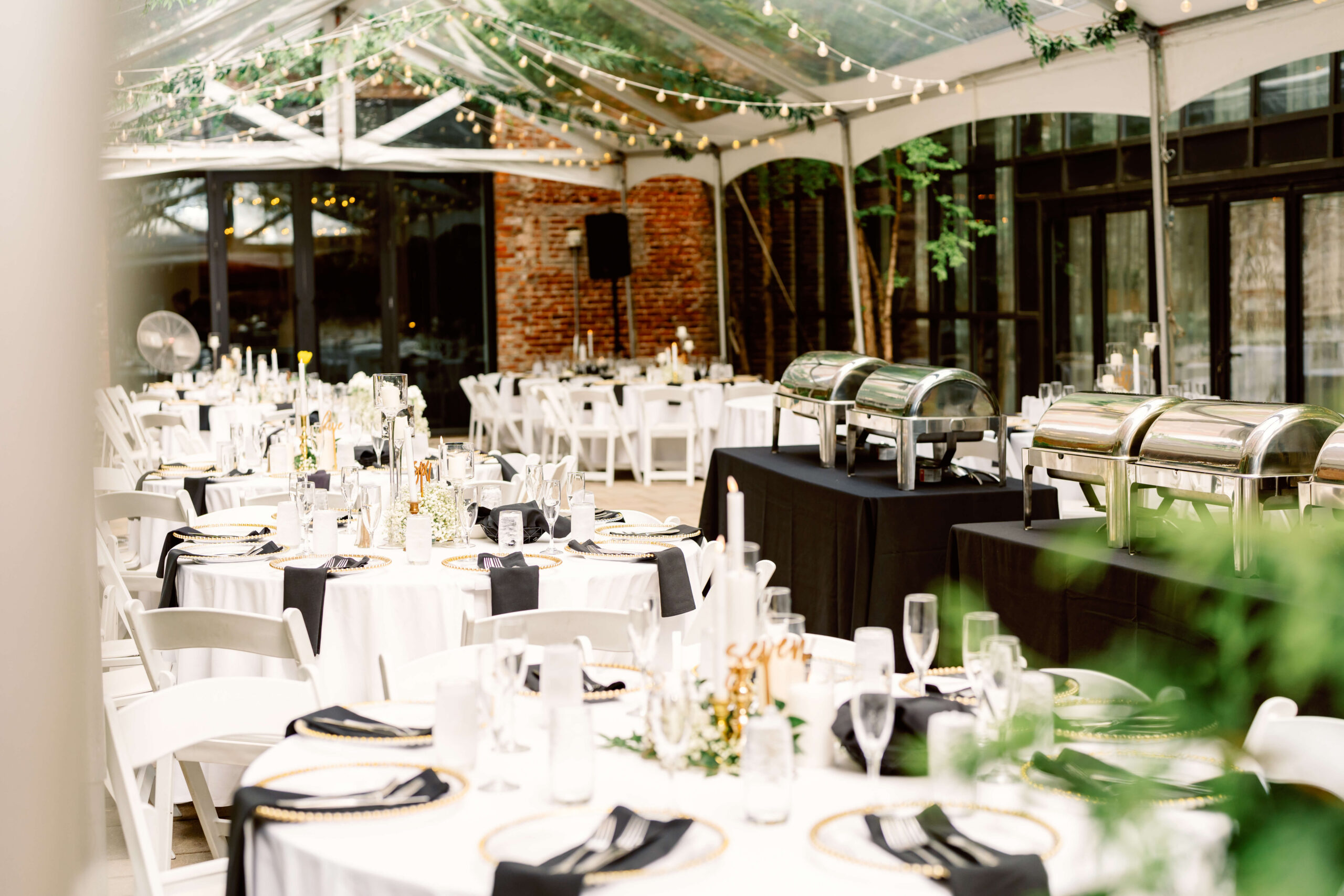 Details of a reception with buffet set up under a clear tent with market lights at one of the cincinnati wedding venues with a view