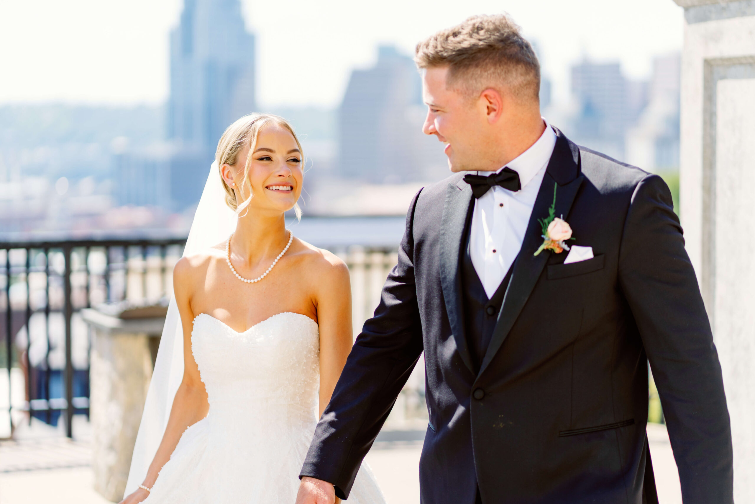 A bride and groom walk holding hands around a patio at one fo the cincinnati wedding venues with a view