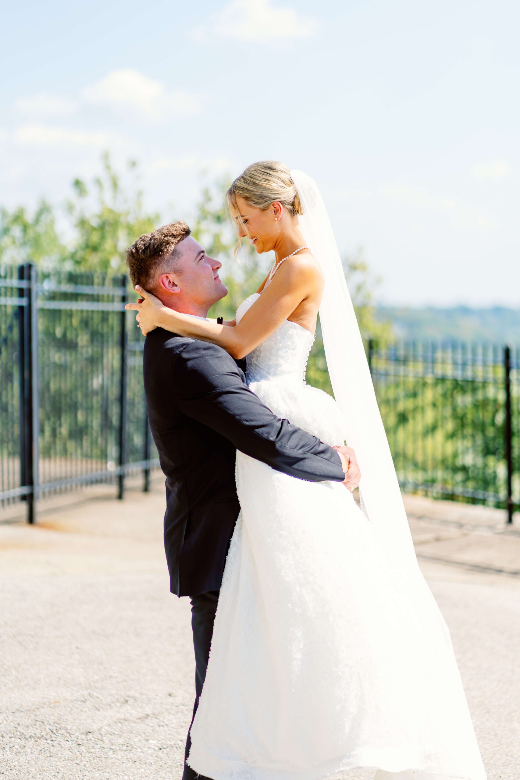 A groom lifts his bride in a happy moment on a patio