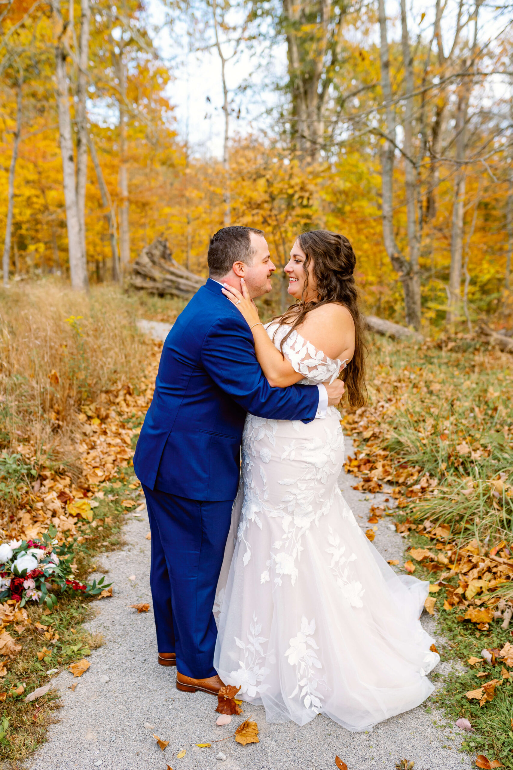 Newlyweds lean in for a kiss in a garden sidewalk