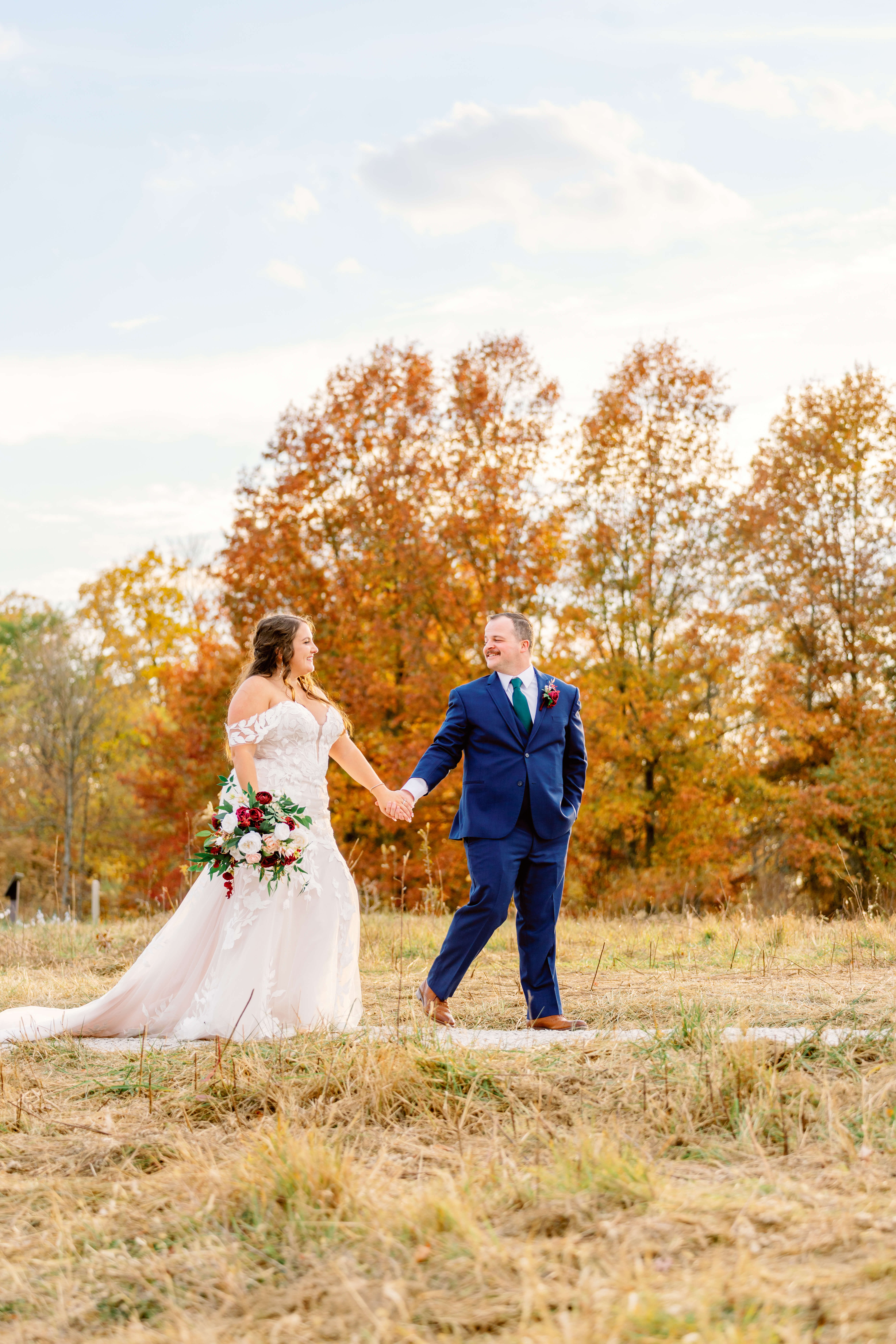 A groom in blue walks his bride on a sidewalk while smiling at her at one of the estate wedding venues in cincinnati