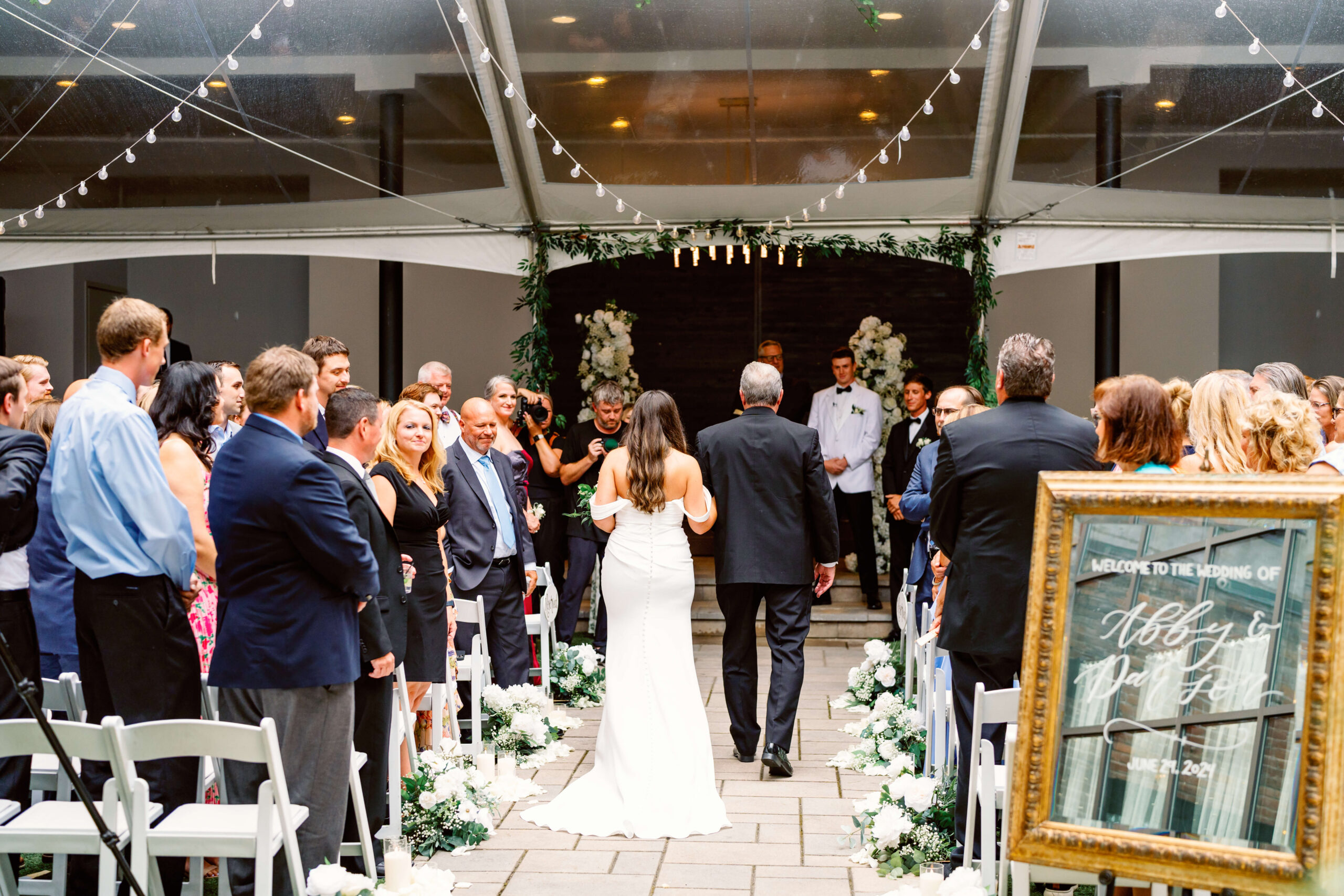 Dad walks his daughter down the aisle to the groom as guests stand watching