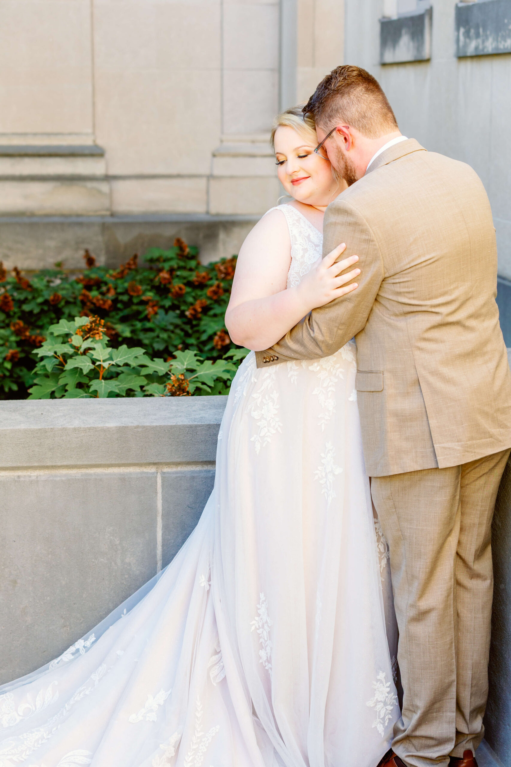 Newlyweds snuggle in a garden corner with smiles
