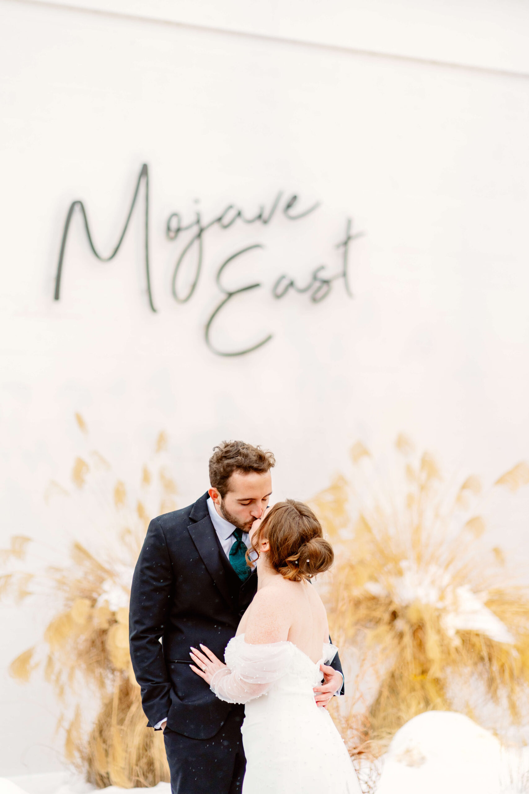 A bride and groom kiss under the Mojave East sign at one of the unique wedding venues in cincinnati