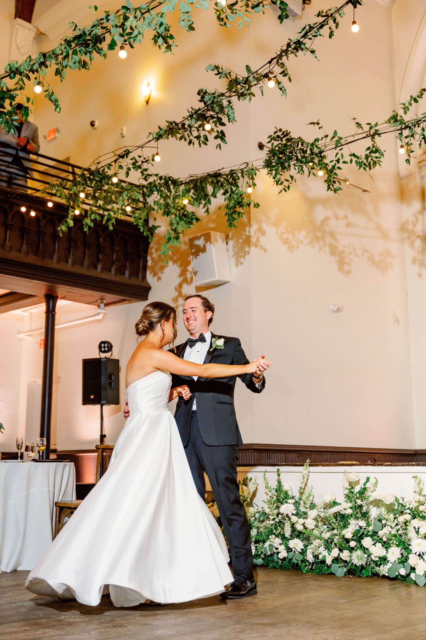 Newlyweds smile while dancing under living chandeliers at one of the unique wedding venues in cincinnati