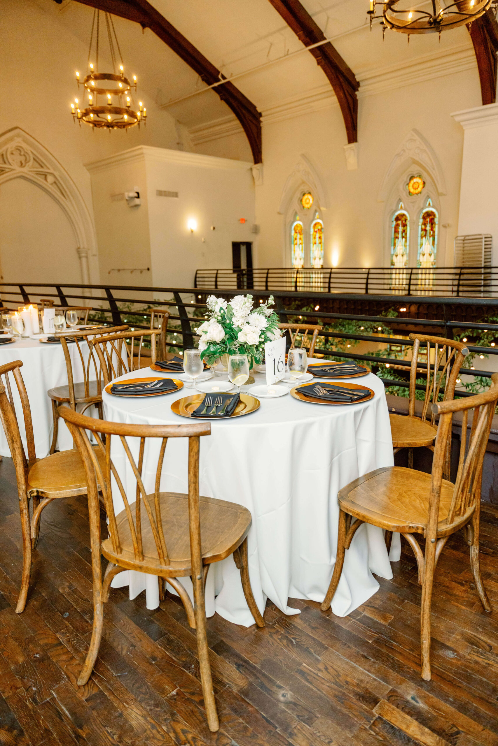 Details of a reception table set up with white linen and wooden chairs on a balcony